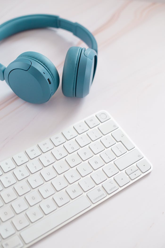 about-02 Minimalist setup featuring blue headphones and a white keyboard on a desk.