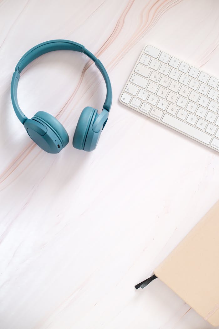 Mastering the First Impression: Your intriguing post title goes here Flat lay of teal headphones, keyboard, and notebook on a desk.