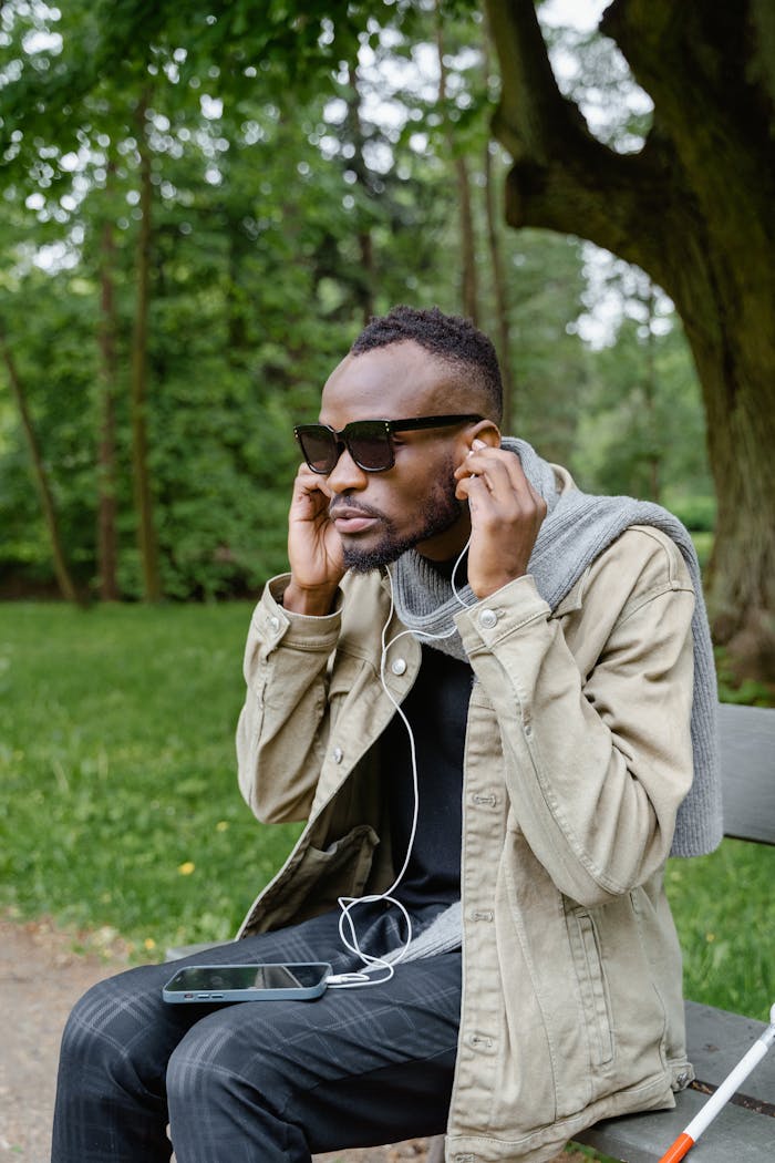 services-02 A man with sunglasses enjoys music in a park, showcasing technology accessibility.